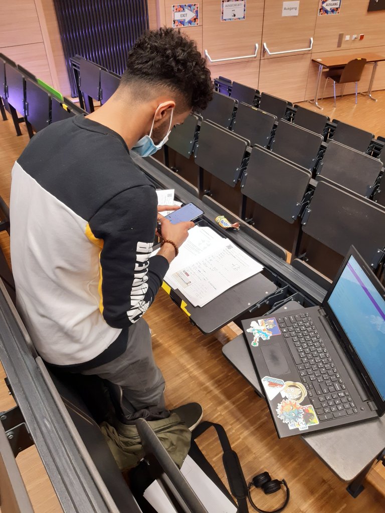Student beim Abfotografieren und Digitalisieren Ihrer handschriftlichen Lösungen am Ende der Open-Book- und Open-Web-Prüfung im Wintersemester 2021/2022